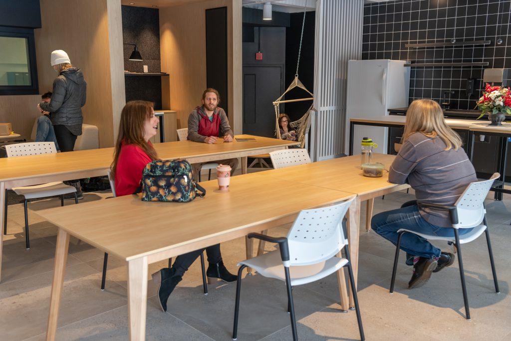 Des employés discutent dans la salle des employés.