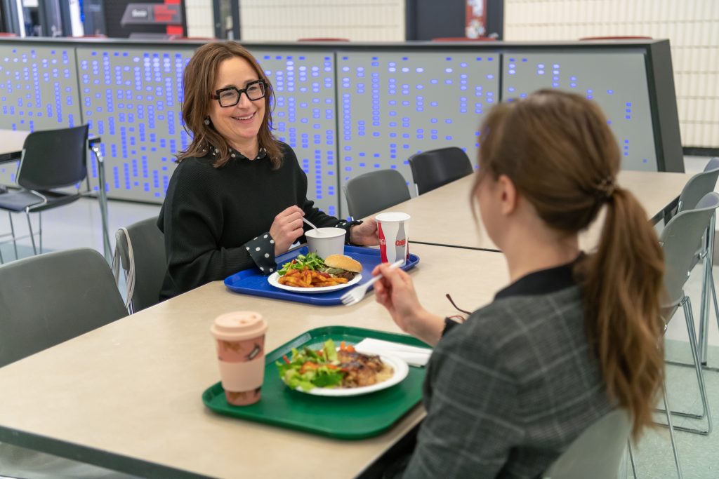Des employés discutent en mangeant dans la cafétéria.