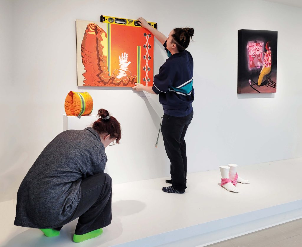 Deux étudiants installant leurs œuvres sur une petite scène.