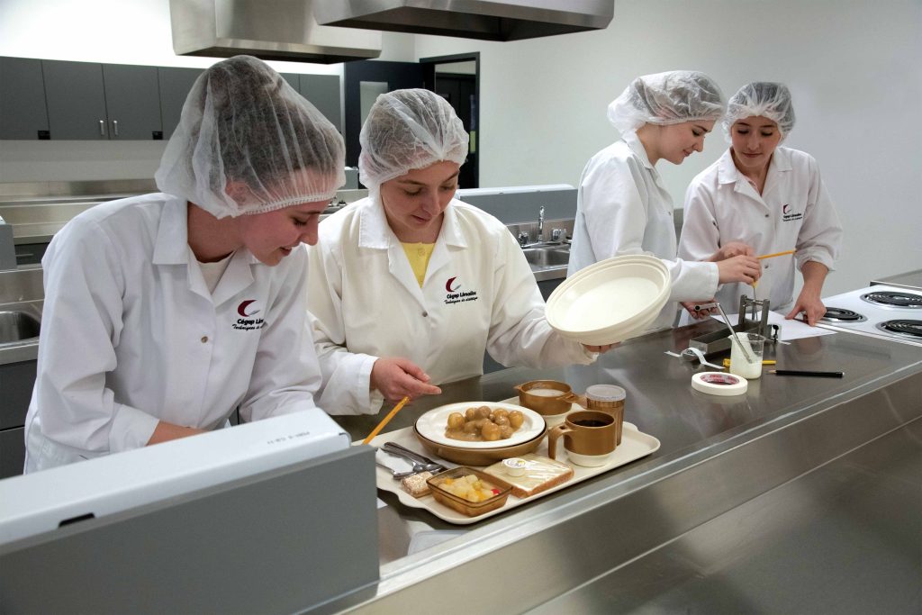 Quatre étudiantes cuisinant des repas dans une cuisine éducative.