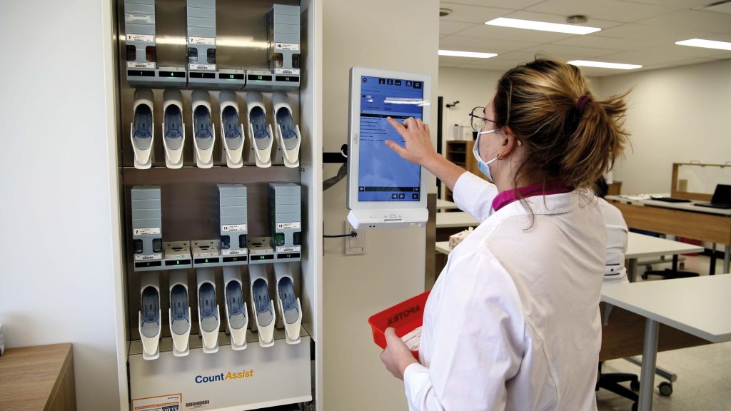 Étudiante en pharmacie devant un écran tactile dans une salle de classe.
