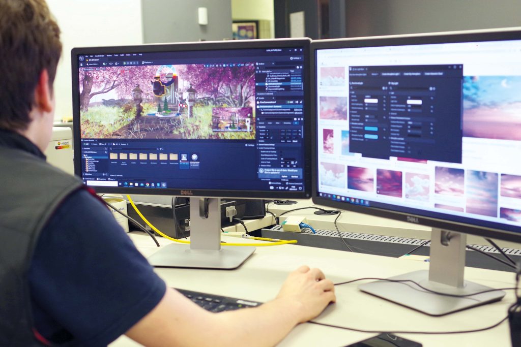 Étudiant devant deux écrans d'ordinateur qui fait un montage 3D.