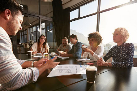 Équipe de six personnes assis à discuter autour d'une table dans une salle de réunion.