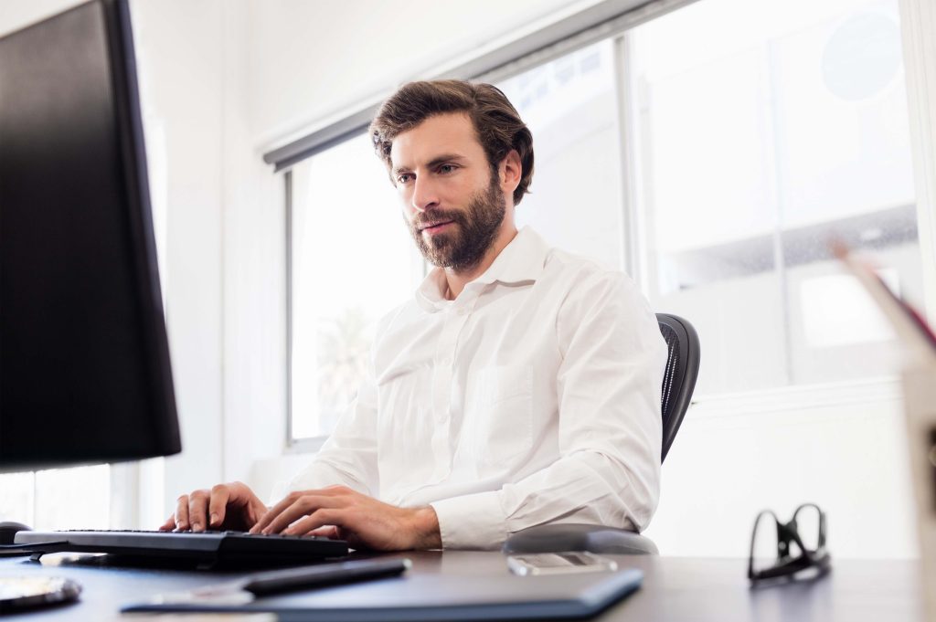 Homme devant un ordinateur, tapant au clavier.