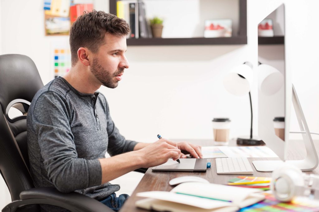 Homme avec une tablette graphique, travaillant à l'ordinateur.