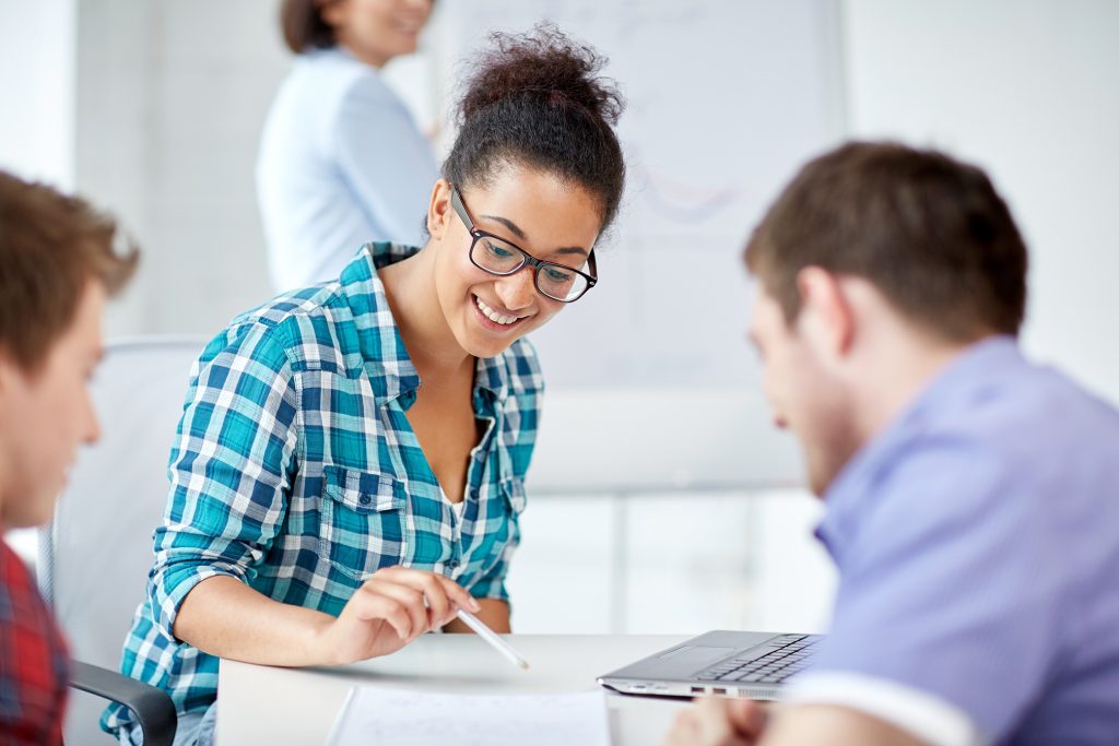 Une femme et deux hommes souriant et regardant une feuille de notes, crayon à la main.