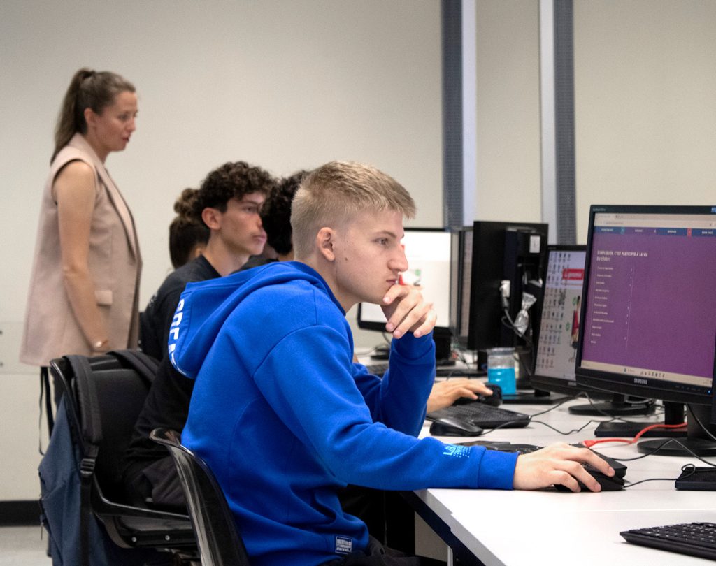 Étudiants internationaux travaillant à l'ordinateur, avec une enseignante qui les supervise.