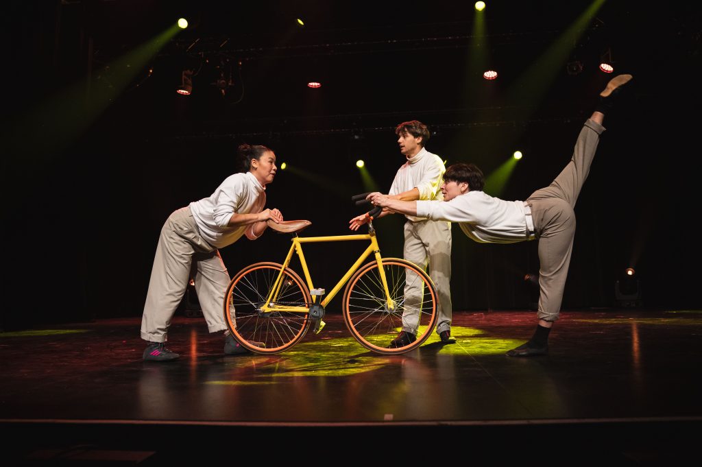 Des étudiants performent sur scène avec un vélo de cirque.