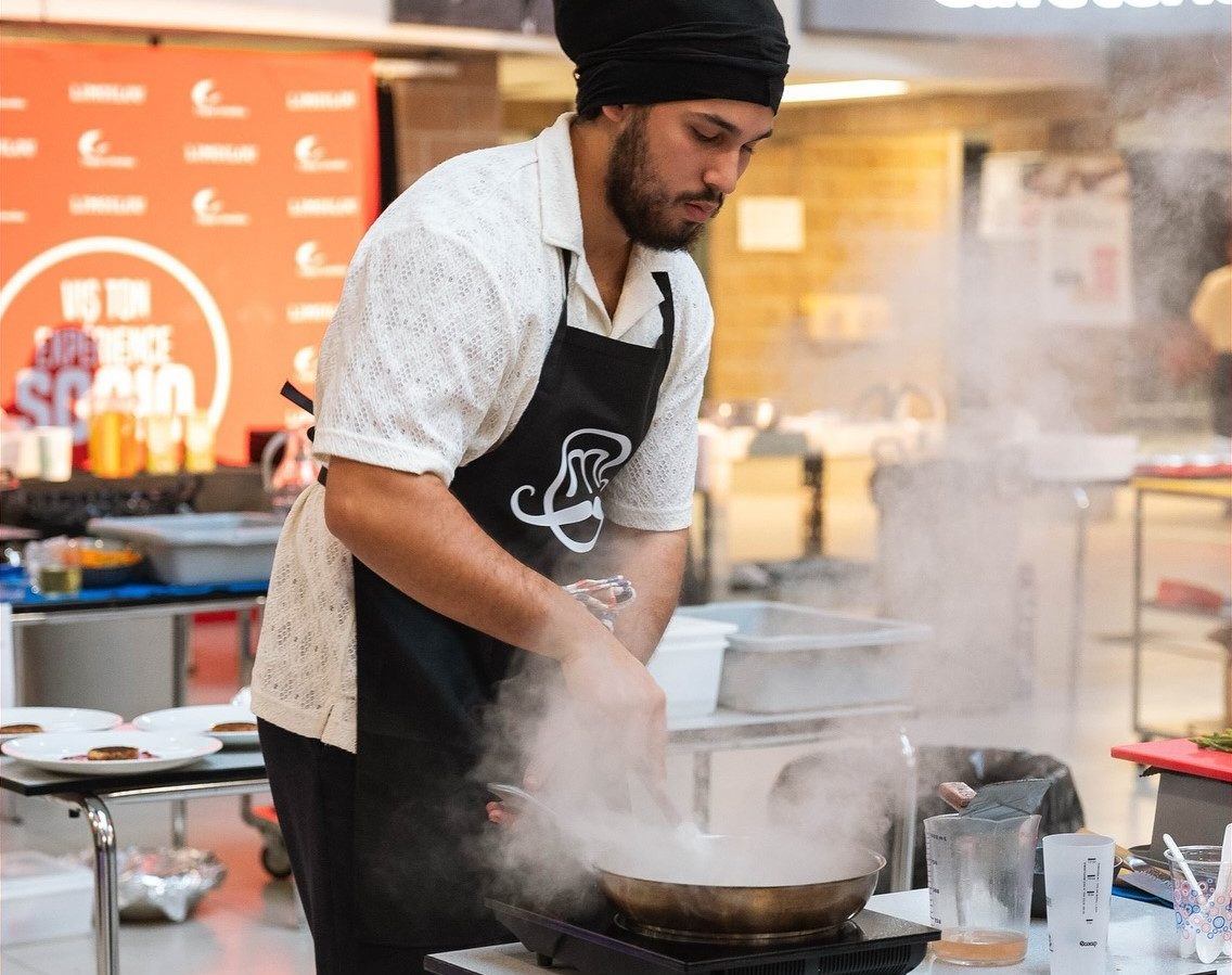 Étudiant qui cuisine devant une poêle avec vapeur